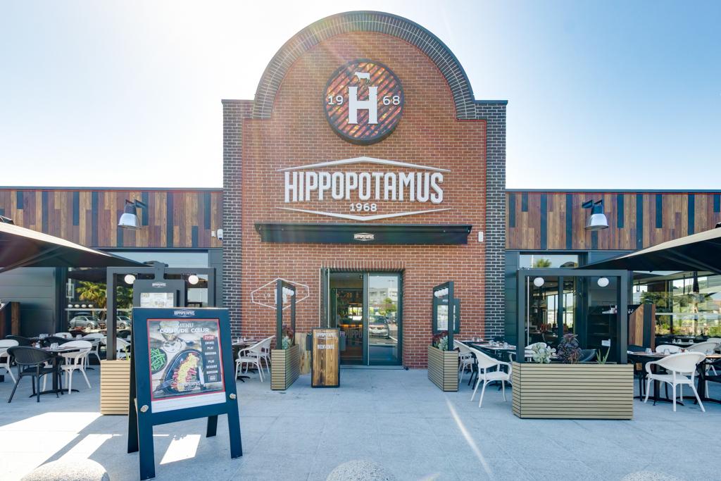 Extérieur d'un restaurant Hippopotamus avec terrasse, façade moderne en briques et grande enseigne indiquant « Hippopotamus 1968 ».