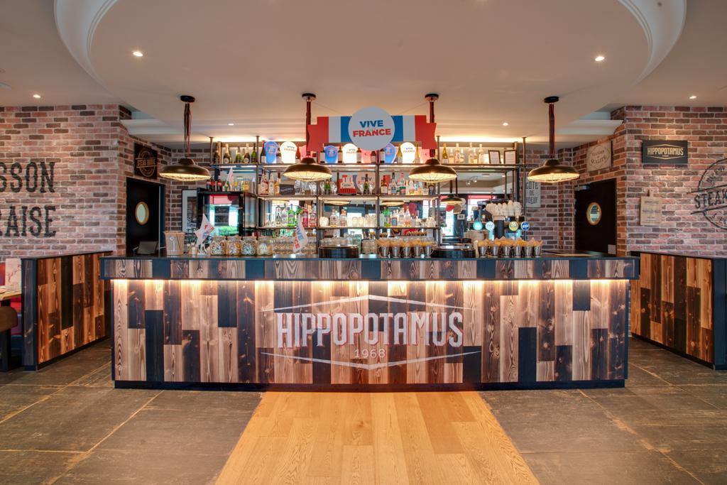 Restaurant Steakhouse avec des touches de bois, des murs en briques, des suspensions lumineuses