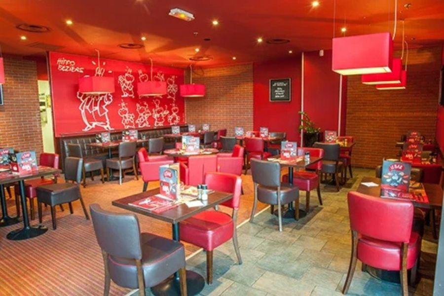 Un restaurant à l'intérieur chaleureux avec des murs et des meubles rouges, des tables bien disposées. Restaurant Hippopotamus